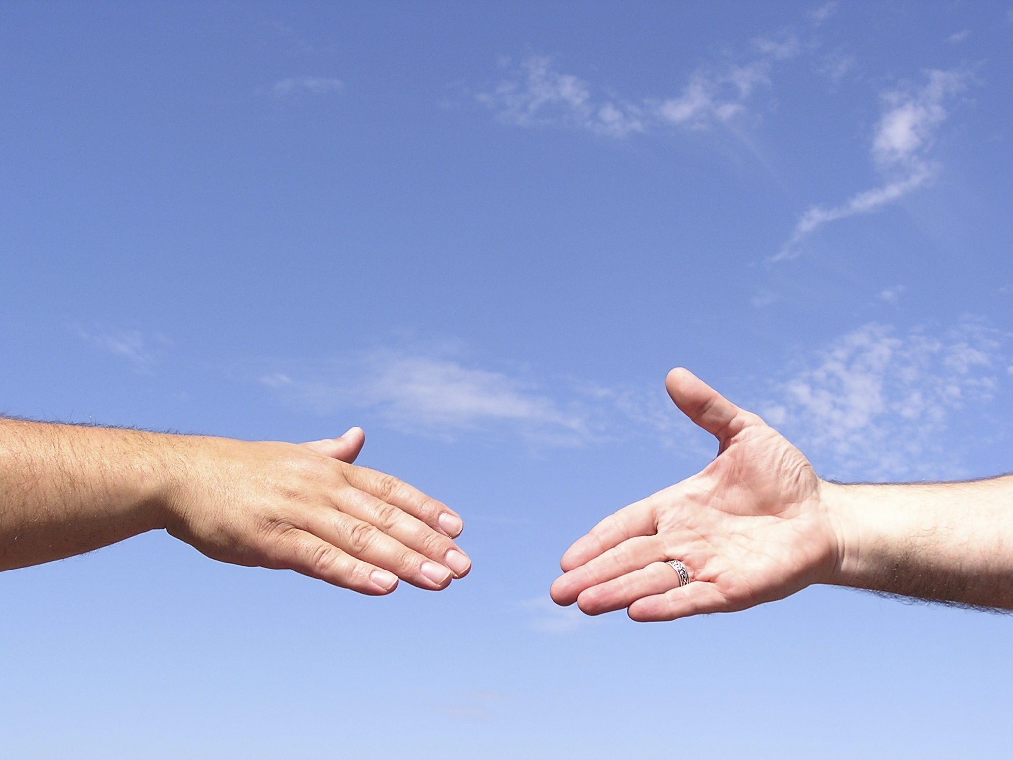 Blue sky with two hands reaching out to each other