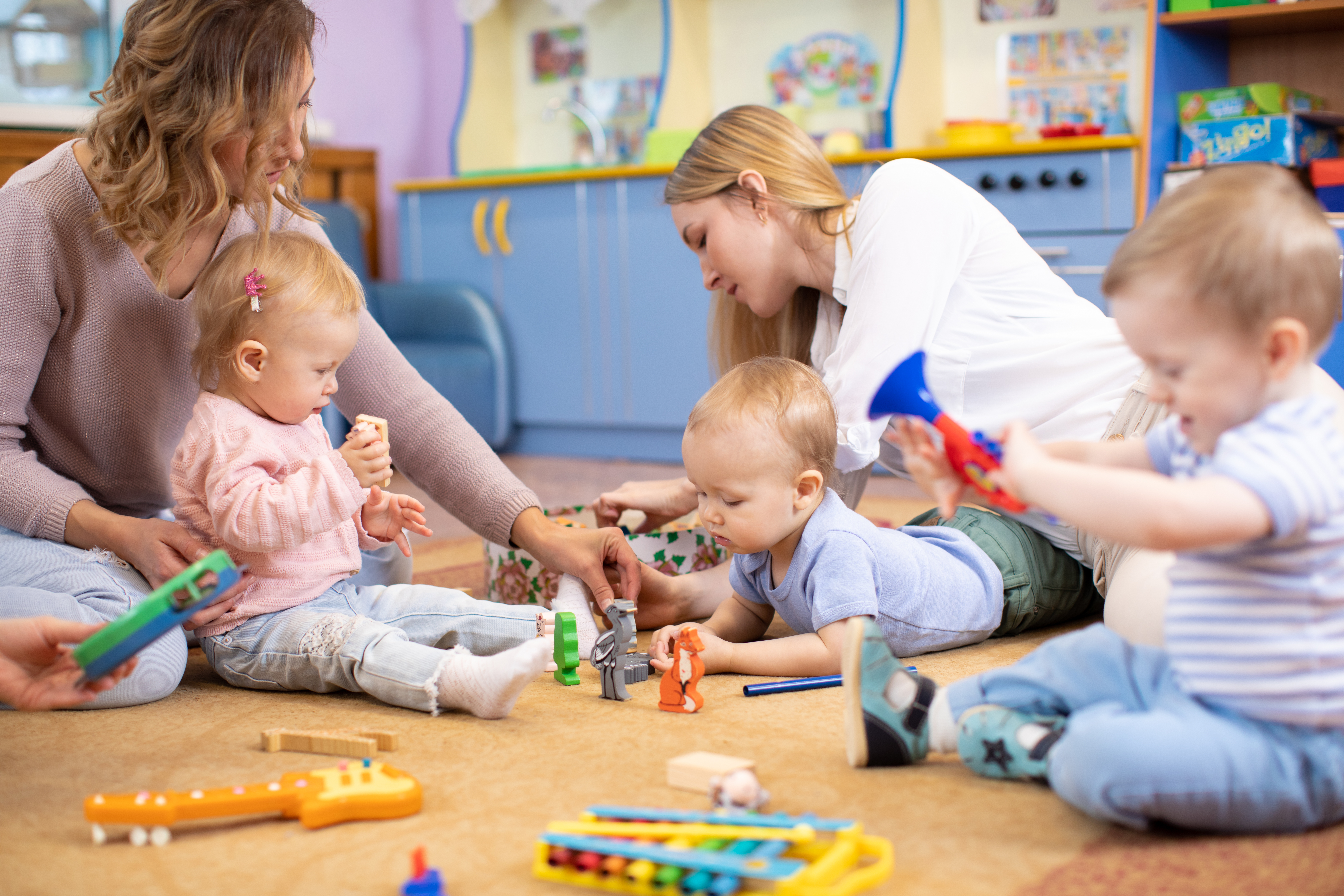 Toddlers playing with their care givers in a nursery at a school